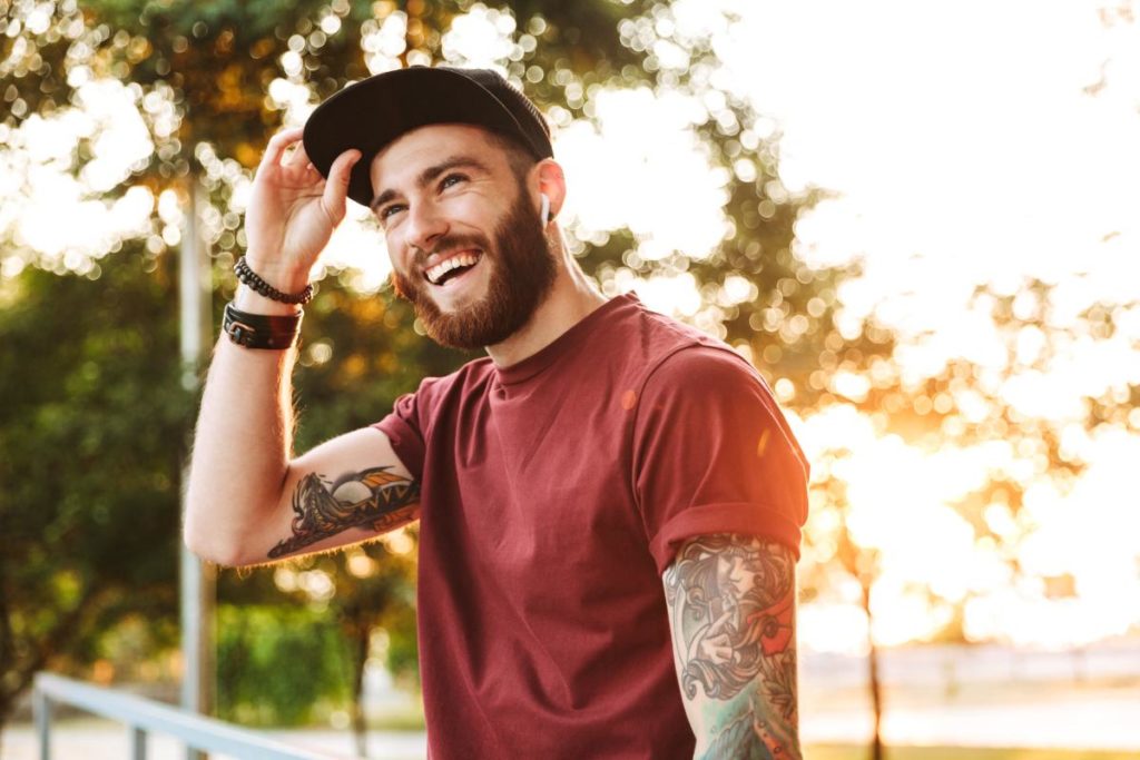 man smiling with tattoos and a hat