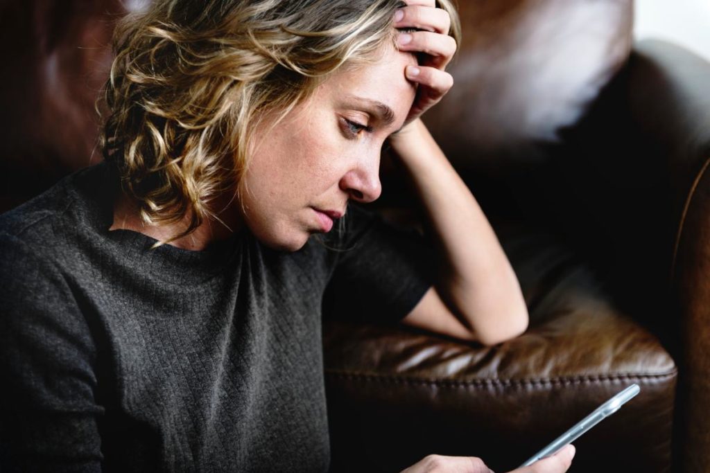 woman looking at phone looking up symptoms of addiction