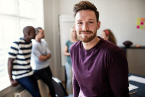 a man smiling and participating in group therapy one of the many benefits of intensive outpatient program