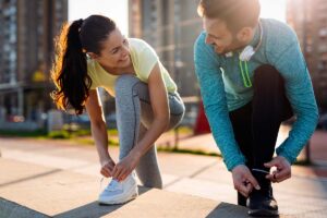 two people tie their shoe laces while about to go for a run and participate in exercise and addiction recovery