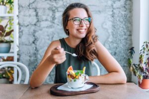 a woman sits down and eats a healthy snack after realizing diet in addiction recovery is very important