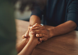 a person holds the hands of another person after discussing treatment options for anxiety
