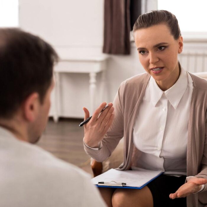 a woman sits with an adult man to discuss how to find a therapist